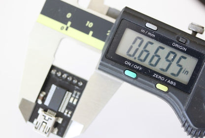 USB to serial converter shown with caliper. The measurement reads .6695 inches. 