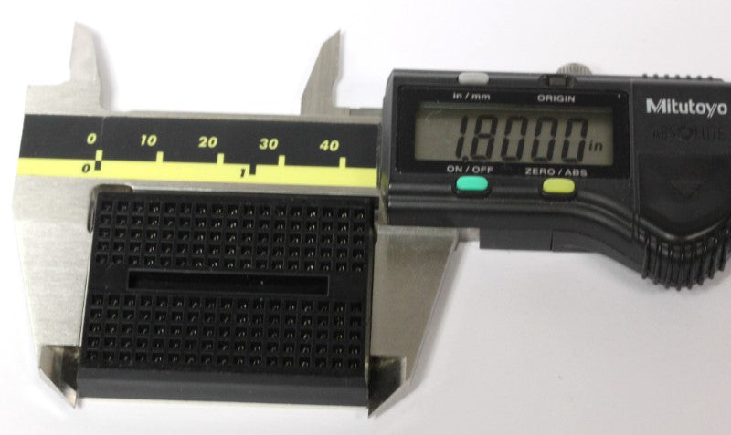 A black Breadboard in a caliper, showing its length. 