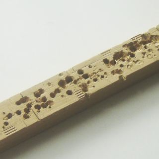 A piece of scrap wood that has many holes, which was used to protect the other furniture.